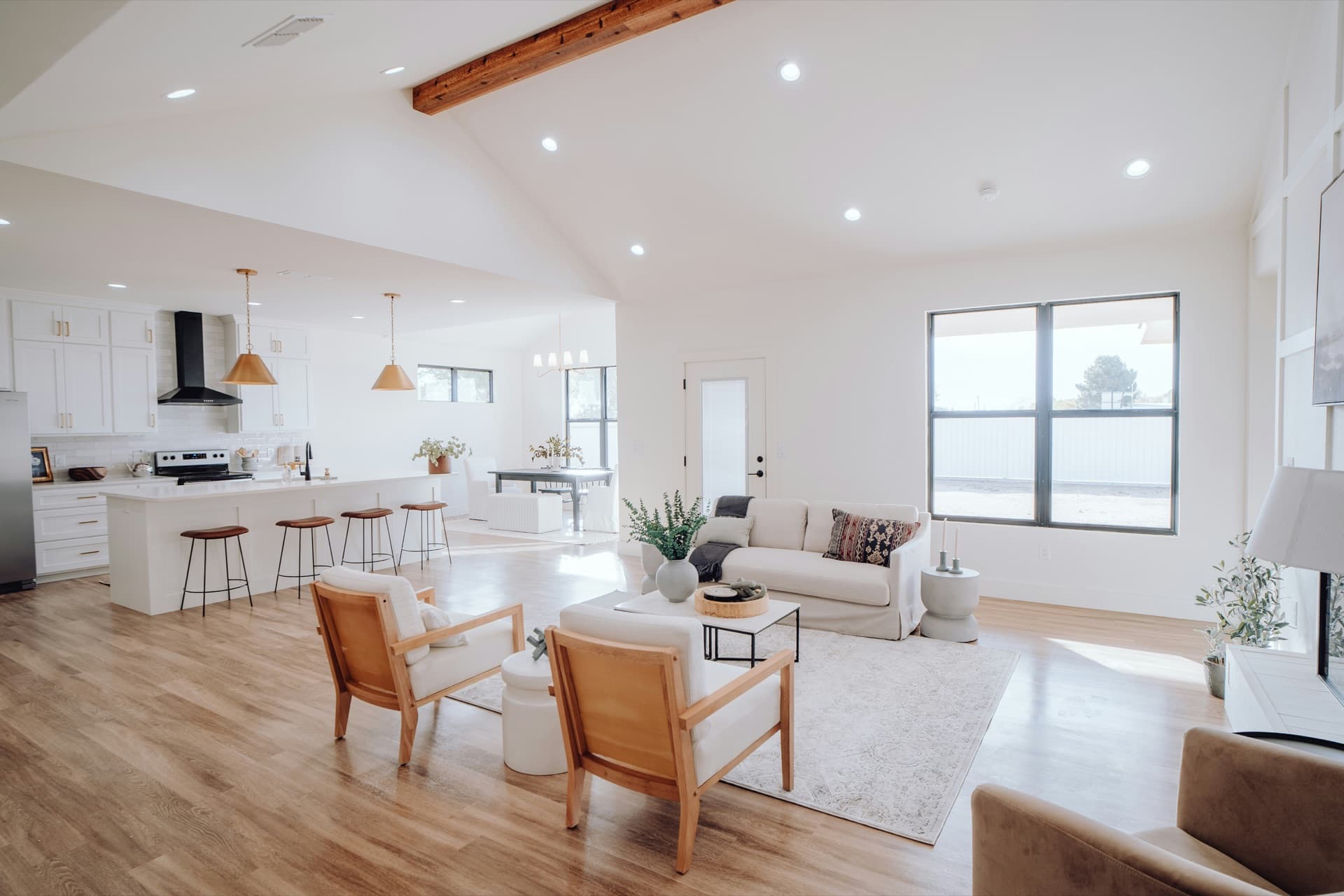 Bright open-plan living room and kitchen with a vaulted, beamed ceiling, a sofa and two armchairs
