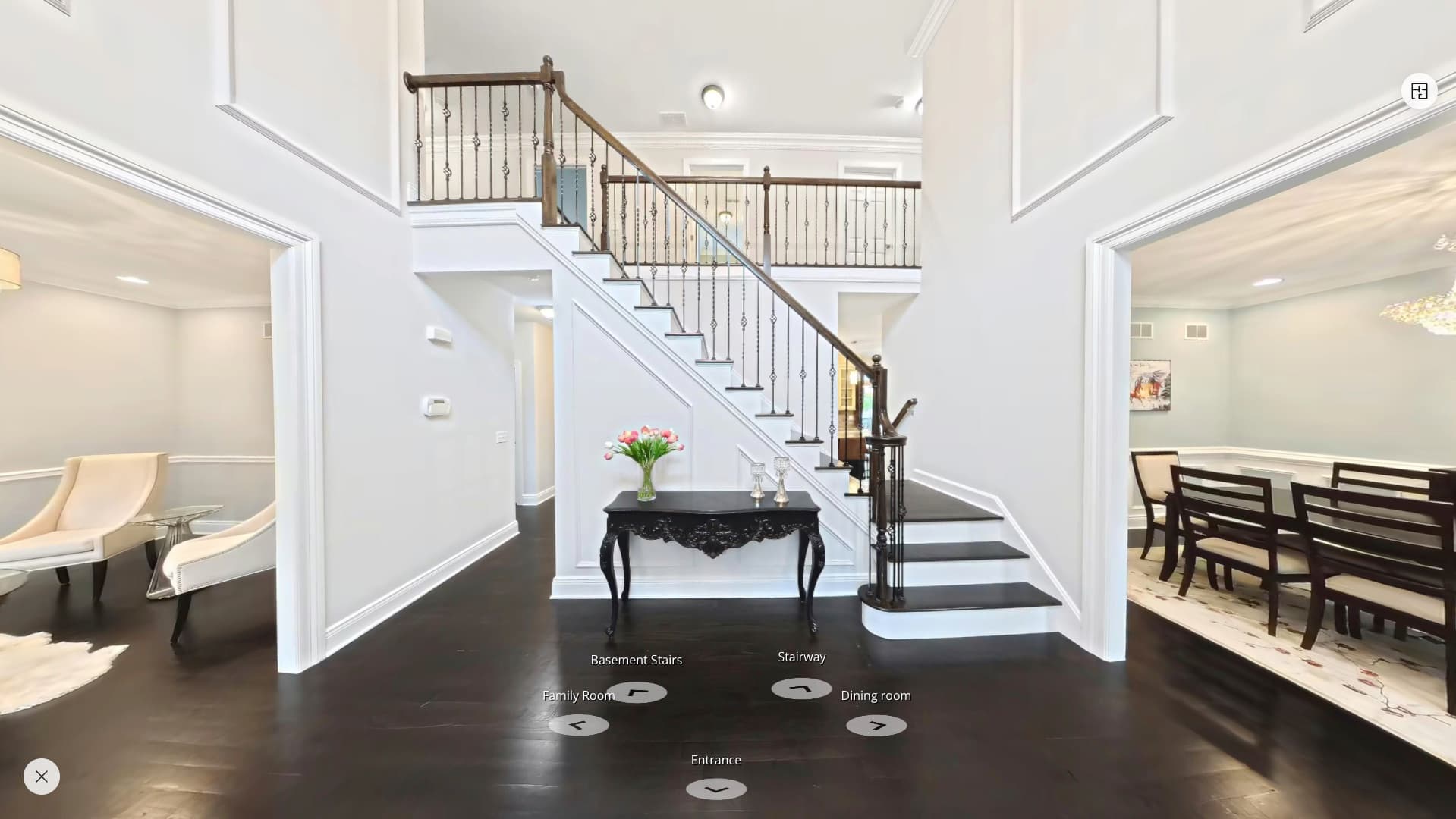 A 3D tour of a two-story foyer with a curved staircase, showing labeled points to move to the next room